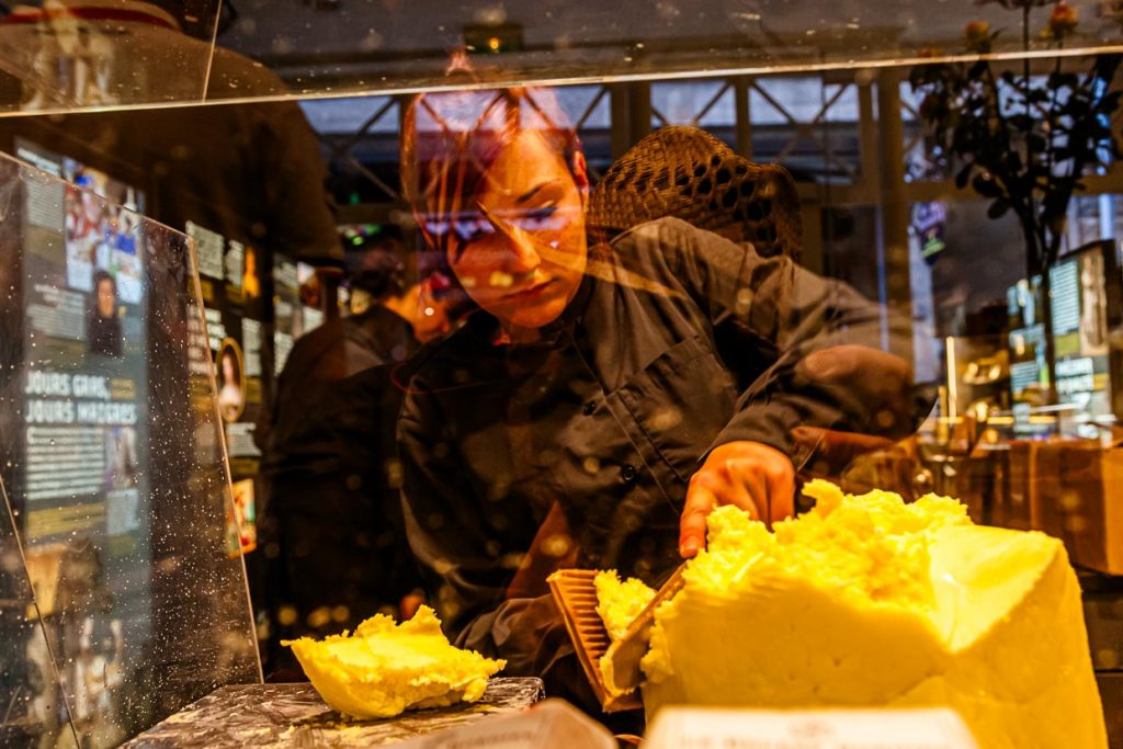 Blick durch die Arbeitstheke im Maison du Beurre. Aus einem Butterblock werden kleine Portionen abgeteilt / © Foto: Georg Berg