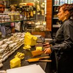 Verkaufstheke im Maison du Beurre von Jean Yves Bordier in Saint Malo. Eine Verkäuferin schlägt die Butter mit zwei Holzpaddeln / © Foto: Georg Berg