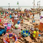 Rollenverteilung im Hafen von Tombo Bay, Sierra Leone. Frauen warten auf die Fischer und ihren Fang. Der einzige Weiße auf diesem Bild: Christiano Ronaldo (CR7) isoliert von den Anderen gedruckt auf einem T-Shirt / © Foto: Georg Berg