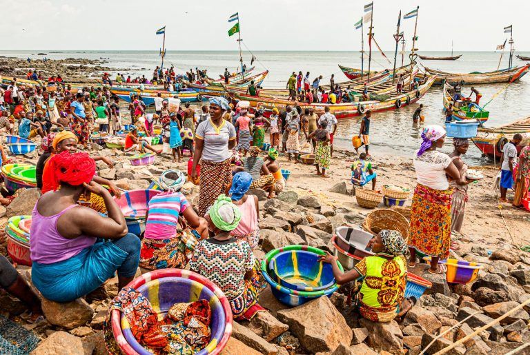 Rollenverteilung im Hafen von Tombo Bay, Sierra Leone. Frauen warten auf die Fischer und ihren Fang. Der einzige Weiße auf diesem Bild: Christiano Ronaldo (CR7) isoliert von den Anderen gedruckt auf einem T-Shirt / © Foto: Georg Berg