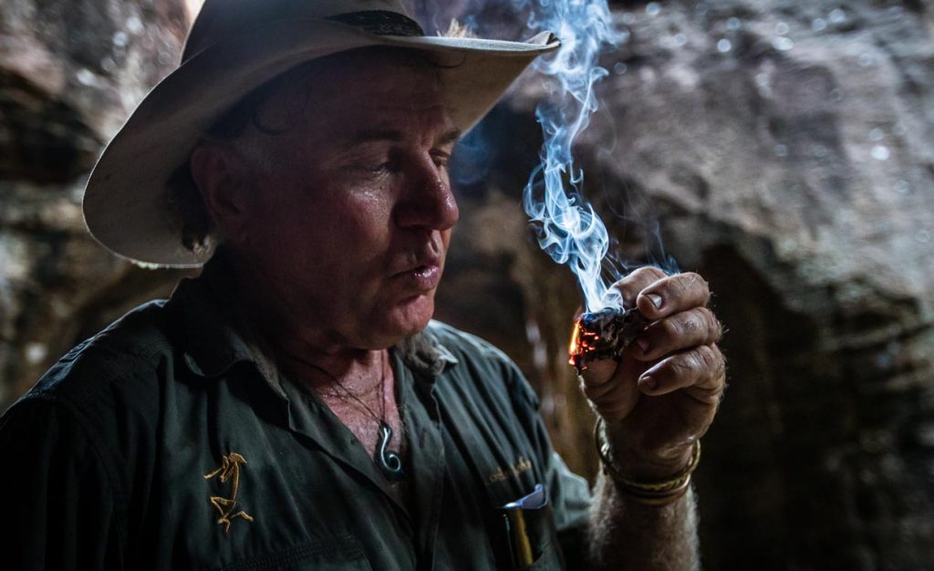 Sab Lord zündet ein von Termiten bearbeitetes Stück Holz an. Ein altes „Hausmittel“ der Aborigines, um mit dem Rauch die Mücken zu vertreiben / © Foto: Georg Berg