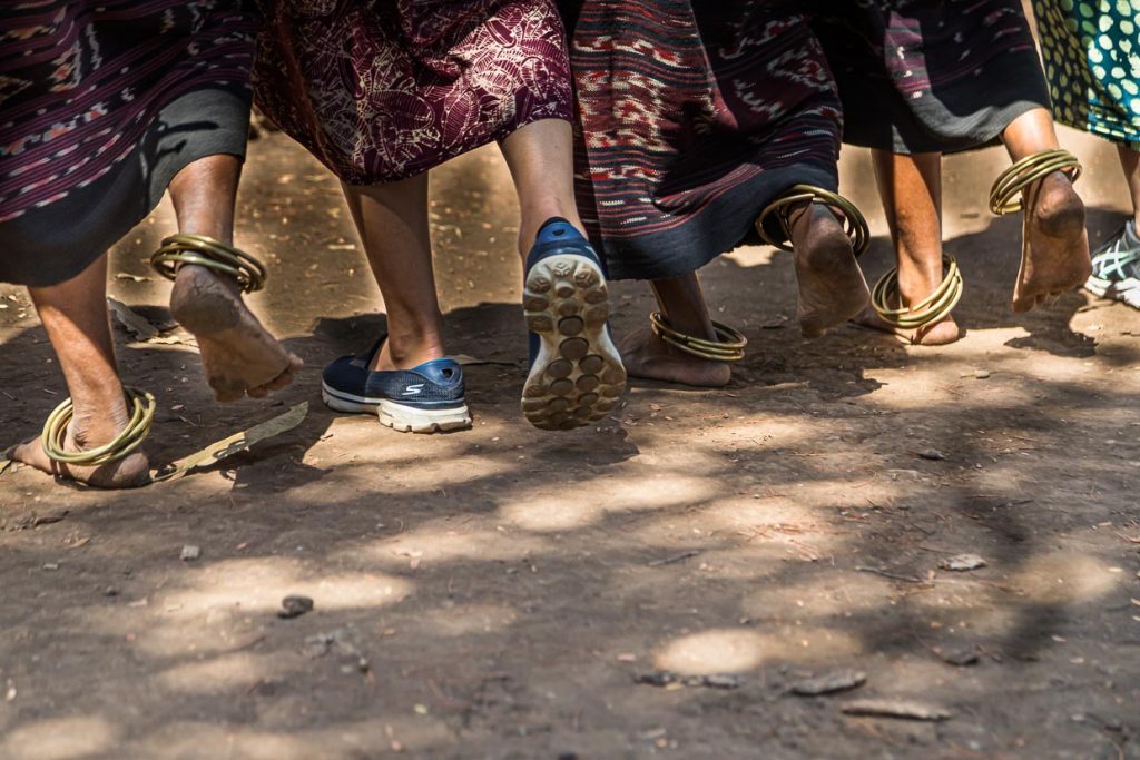 Mit Fußringen geben die Einheimischen den Rhythmus vor. Dadurch lernen auch ihre Gäste die richtige Schrittfolge / © Foto: Georg Berg