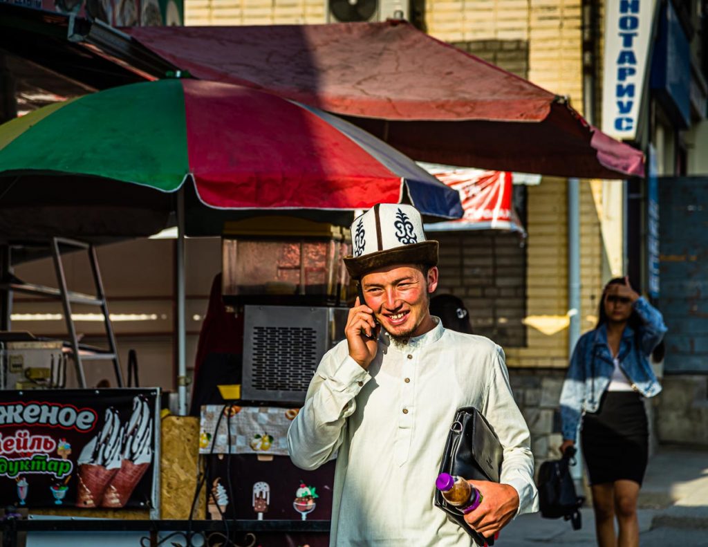 Junger kirgisischer Geschäftsmann unterwegs mit Kalpak, dem traditionell kirgisischen Hut aus weißem Wollfilz / © Foto: Georg Berg