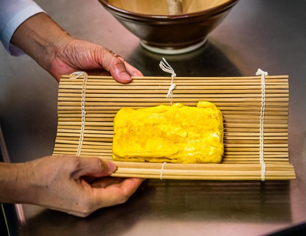 Das angebratene Omelett wird in einer Bambusmatte in Form gebracht. So lässt sich der Laib besser in Portionen schneiden / © Foto: Georg Berg