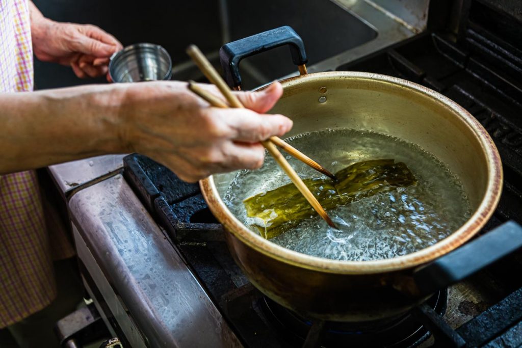 Im ersten Schritt auf dem Weg zu einer vor Umami strotzenden Misosuppe wird Kombualge in aufgekochtes Wasser gegeben / © Foto: Georg Berg