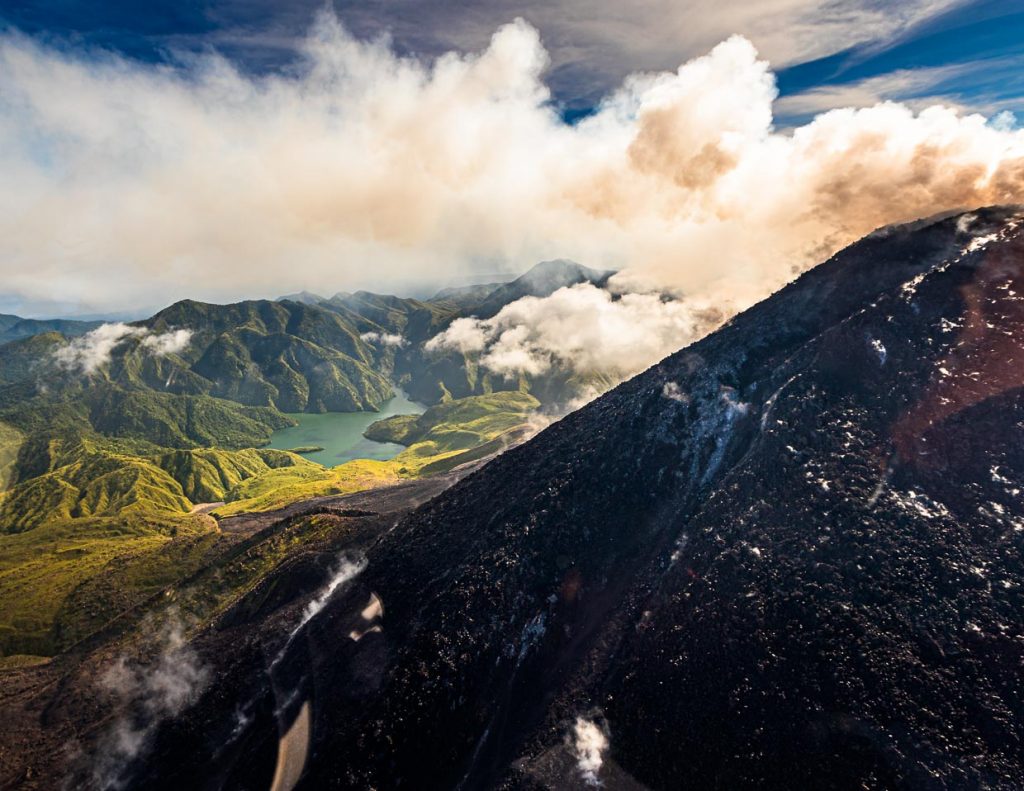 Hinter dem aktiven Bagana Vulkan taucht die mit Wasser gefüllte Formation des Lake Billy Mitchell auf / © Foto: Georg Berg