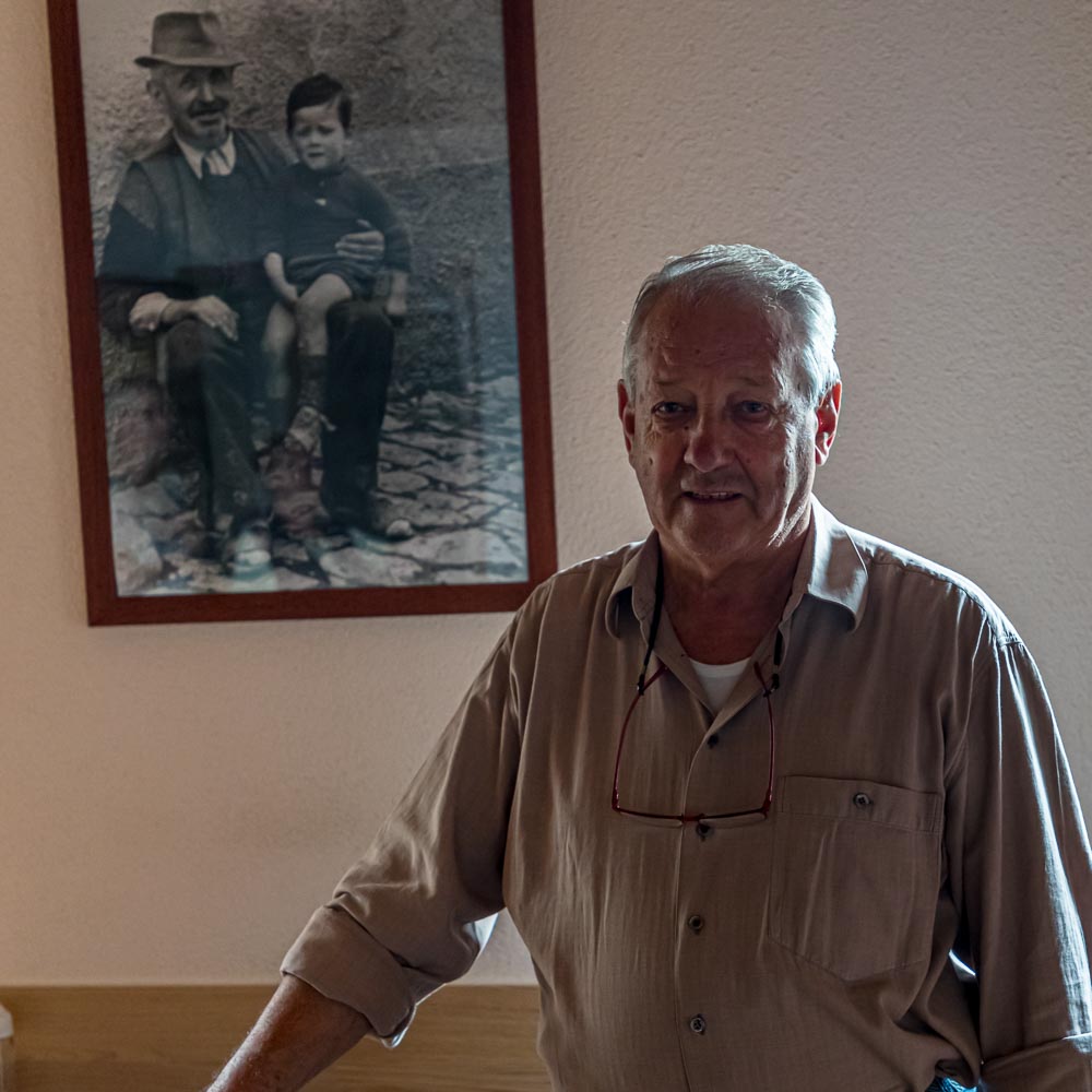 Geurino Pifaretti, Inhaber der Osteria Manciana vor dem Foto, das ihn zusammen mit seinem Großvater zeigt / © Foto: Georg Berg