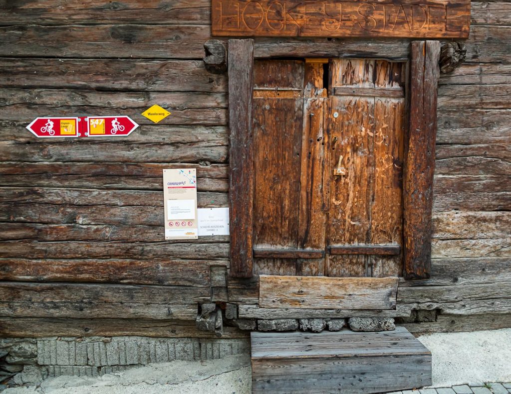 Ausgewiesene Mountainbike-Strecken finden sich im ganzen Wallis und sind oft an alten Hauswänden ausgeschildert. / © Foto: Georg Berg