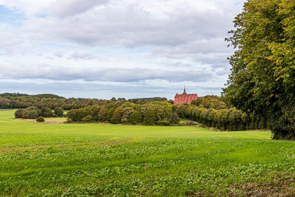 Schloss Tranekær leuchtet rot aus der Parkanlage heraus. Seit dem 13. Jahrhundert gibt es das Schloss an dieser Stelle, das von den Beamten des Königs als Dienstsitz genutzt wurde / © Foto: Georg Berg