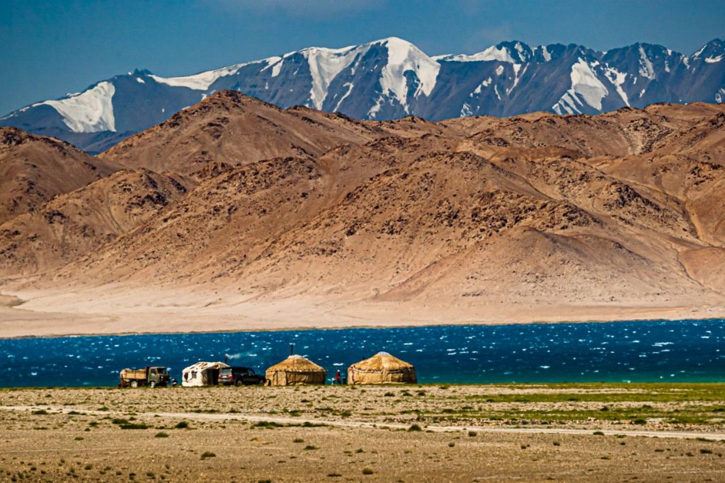 Jurten der kirgisischen Nomaden am tadschikischen Karakul-See, der mit seiner dunklen Farbe einen schönen Kontrast zu den schneebedeckten Gipfeln bildet / © Foto: Georg Berg
