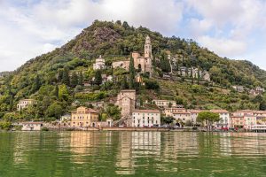 Vom Wasser aus betrachtet: Die Kirche Santa Maria del Sasso von Morcote, darunter die historische Altstadt. Viele kleine Restaurants säumen die Uferpromenade / © Foto: Georg Berg