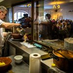 Chef Eric Rousselot bereitet das berühmte Cassoulet Imperial in der Hostellerie Etienne zu, die seit 1956 als Familienbetrieb geführt wird. Dicht an dicht sitzen die Gäste im Restaurant Etienne auch an einem Wochentag im November. Eric Rousselot gießt noch etwas Boullion an, bevor die nächste Cassole an den Tisch geht / © Foto: Georg Berg