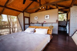 Doppelbett im australischen Outback-Chic hinter den Wellblechwänden der Bamurru Plains Lodge. Wind weht durch die Fliegengitter und keiner vermisst Klimaanlage oder WLAN / © Foto: Georg Berg