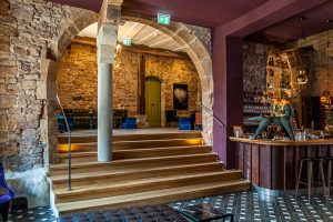 Jeder Bogen ist ein Geschenk, sagt Mitinhaberin Kirstin Kleinkauf. Dieser Bogen, der den Eingangsbereich mit Bistro und Bar verbindet, ist ein besonderer Blickfang, an dem kein Gast achtlos vorbeigeht. Eine kleine Beobachtung am Rande: Beim Betreten der Bar interessieren sich die Männer mehr für die Statik des alten Steins, während die Frauen ihren Blick über die samtigen Sessel und funkelnden Lampen schweifen lassen / © Foto: Georg Berg