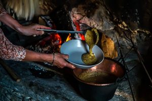 In Cerentino kann man im aufwendig renovierten historischen Patrizierhaus Cà Vegia wohnen, mit jahrhundertealten Originalmöbeln, aber ohne Strom. Polenta wird über dem offenen Feuer zubereitet, Circolo della Rovana, Schweiz / © Foto: Georg Berg