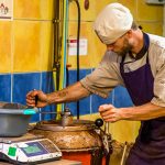 Ein Mitarbeiter der Chocolaterie Frigoulette verschließt den Mélangeur, in dem die abgewogenen Zuten gemischt und erwärmt werden. Bei Frigoulette werden keine tierischen Fette wie Milch, Sahne oder Butter verarbeitet. Auch Palmöl kommt nicht zum Einsatz. Stattdessen 68 prozentiger Kakaoanteil und echte Kakaobutter aus São Tomé / © Foto: Georg Berg
