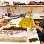 Am kühlen Vormittag wird der Bestseller der Schokoladen-Manufaktur Frigoulette von Hand in goldenes Papier verpackt. Malakoff-Pralinen, Nuss-Nougat-Pralinen mit 68  Kakaoanteil und gerösteten Haselnüssen. Im Sommer läuft die Produktion für Weihnachten. Frigoulette beliefert Geschäfte in ganz Frankreich mit Malakoff-Pralinen / © Foto: Georg Berg