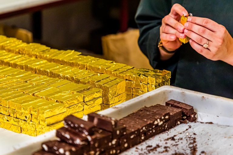 In Handarbeit wird der Bestseller der Schokoladen-Manufaktur Frigoulette in goldenes Papier verpackt. Die Malakoff Praline der Chocolaterie Frigoulette ist in ganz Frankreich erhältlich und besonders beliebt zu Weihnachten. Malakoff gehört zu den geschnittenen Pralinen, die ohne eine zusätzliche Hülle um den Kern auskommen. Die gerösteten Haselnüsse verleihen der Praline eine knusprige Konsistenz / © Foto: Georg Berg