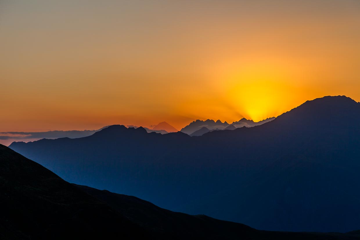 Auf der Khevsureti-Seite unterhalb des Atsunta-Pass in Georgien. Im Sonnenuntergang sieht man weit hinter der Gebirgskette den Berg Kasbek / © Foto: Georg Berg