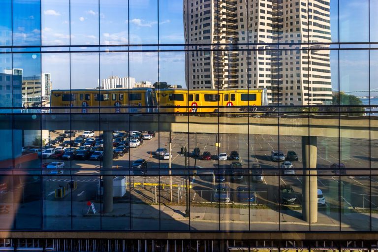 Spiegelung des Detroit  People Mover. Es ist ein 4,7 Kilometer langes, automatisch betriebenes Hochbahnsystem durch die Innenstadt von Detroit. Fahrgäste der Ringlinie sind Touristen und Arbeitnehmer aus den Geschäften und Büros der Innenstadt. Die Fahrt kostet einen Vierteldollar (Quarter) und bietet einen interessanten Blick auf die Gebäude in Downtown Detroit  / © Foto: Georg Berg