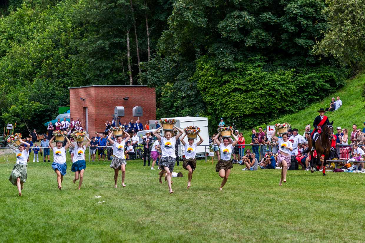 Des lycéennes participent à la course de Waterkübel. Lors de cette course, des jeunes femmes de la neuvième et de la dixième classe du centre de formation de Wildberg s'affrontent dans une course avec des seaux d'eau sur la tête. Cette course fait partie intégrante de la course des bergers et symbolise les anciennes tâches des bergères et des bergers qui devaient apporter de l'eau pour les hommes et les animaux. Elle rappelle le dur travail physique et l'habileté qui étaient nécessaires dans le quotidien de la bergerie / © Photo : Georg Berg