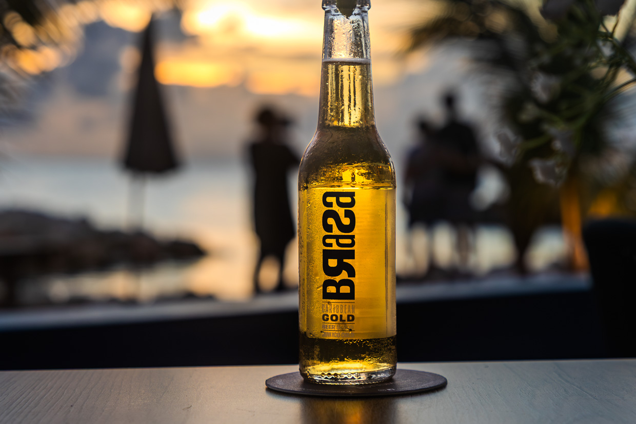 Bottle of Brasa beer in the sunset on Curaçao. This beer brand means hug and has existed since the Covid epidemic during which there were too few hugs / © Photo: Georg Berg