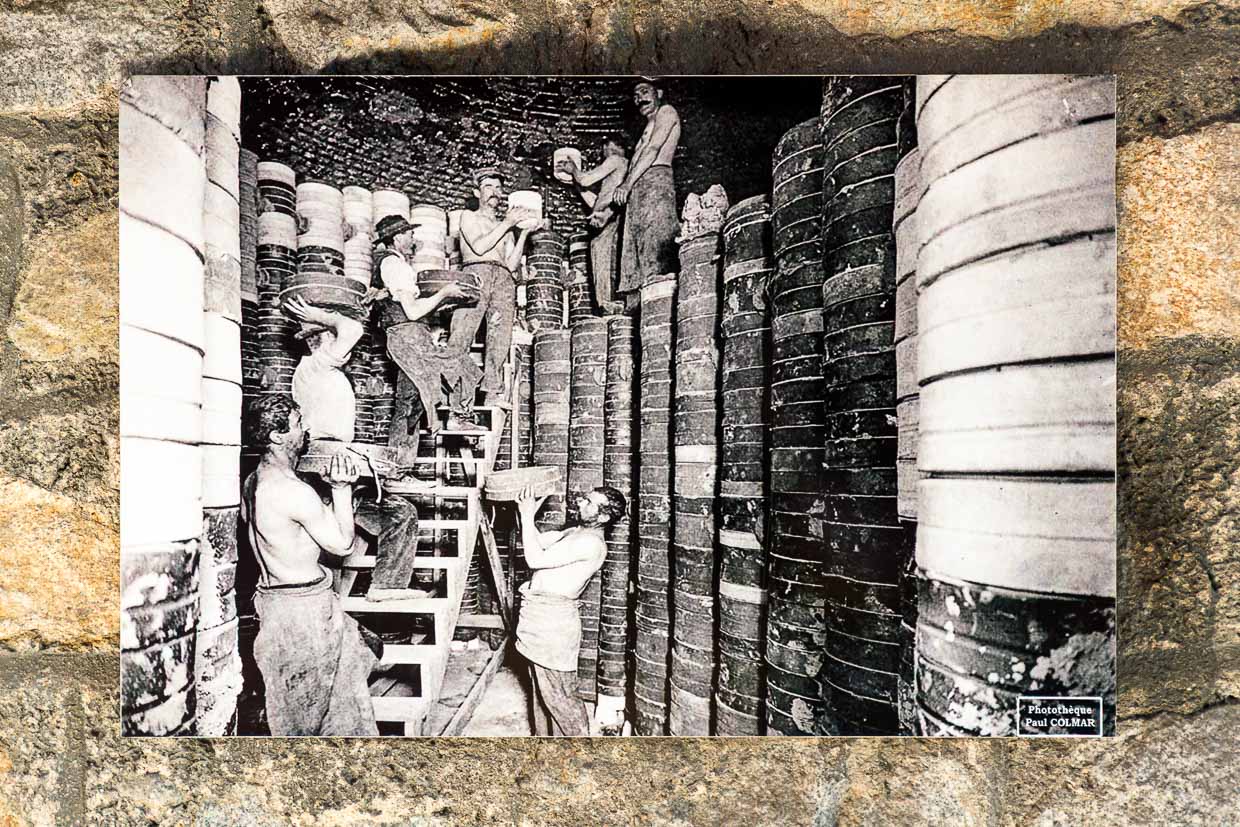 Alte Postkarte aus dem Museum Four des Casseaux in Limoges zeigt ein Foto von Paul Colmar: Fabrikarbeiter packen den Ofen für den zweiten Brand, die schweren Tonformen, in denen jeweils ein Porzellanrohling liegt, wurden meterhoch in den großen Ofen gestapelt / © Foto: Georg Berg