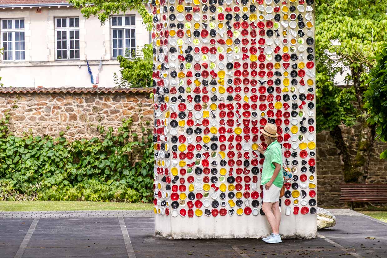 Kunstinstallation  „Une Suite“ von den Künstlern Haguiko und Jean-Pierre Viot. Sie besteht aus farbigen, teils deformierten Porzellanschälchen, die an einer hohen, weißen Betonstele aufgehängt sind. Insgesamt umfasst das Werk etwa 600 Porzellanschalen in verschiedenen Farben und Formen, Musée National Adrien Dubouché in Limoges / © Foto: Georg Berg