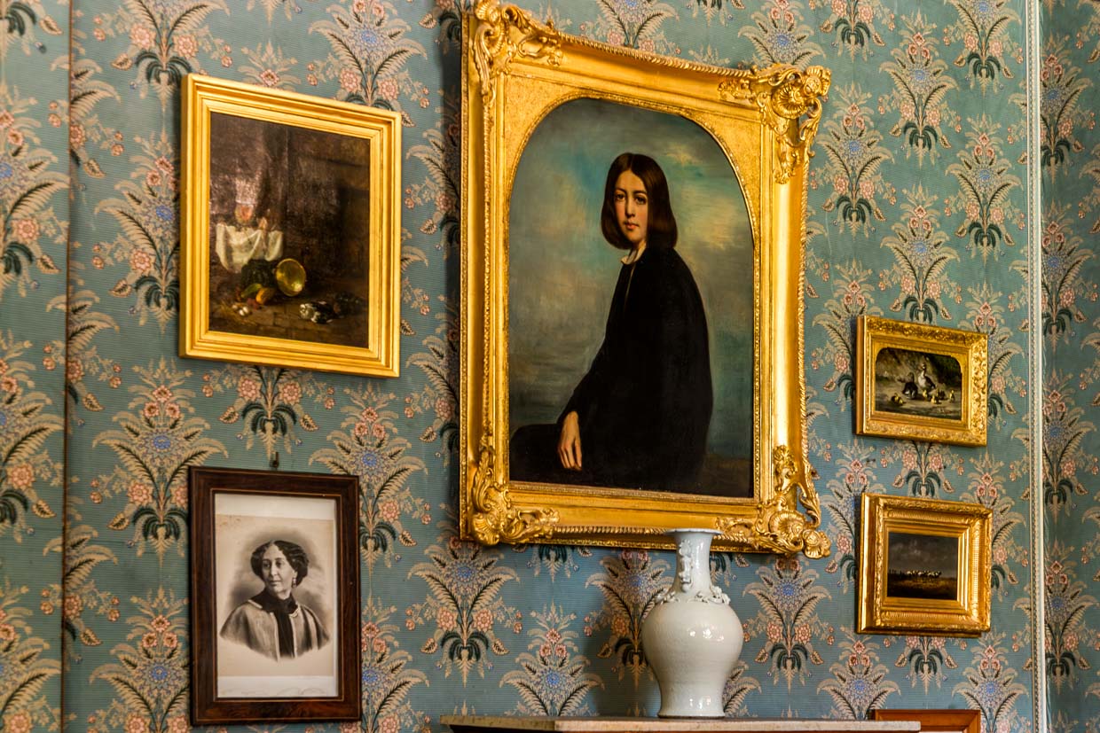 Salon im George-Sand-Haus in Nohant mit Portraits von George Sand und ihrer Familie, hier groß im Bild das Portrait von George Sand als junge Frau / © Foto: Georg Berg
