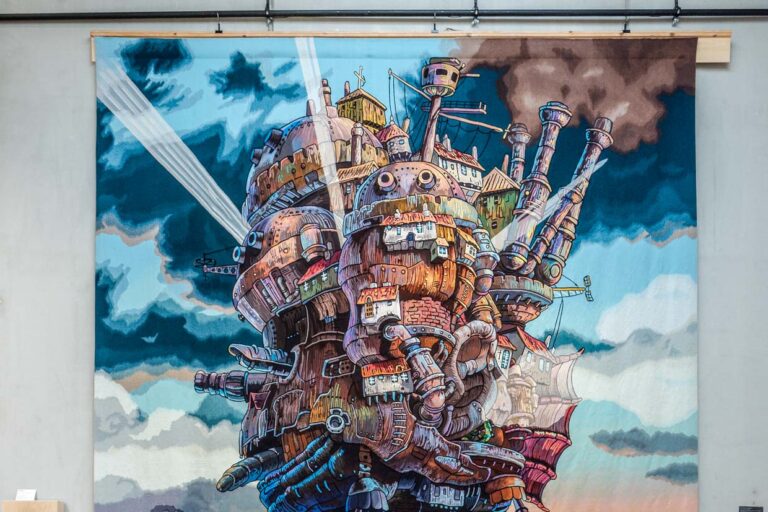 Gewebte Abenteuer in den Ausstellungsräumen der Cité internationale de la tapisserie Aubusson. Hier „The moving castle at sunset“  aus dem Animefilm von 2004 Howl’s Moving Castle. Gewebt in Aubusson ab März 2022 bis Februar 2023 / © Foto: Georg Berg