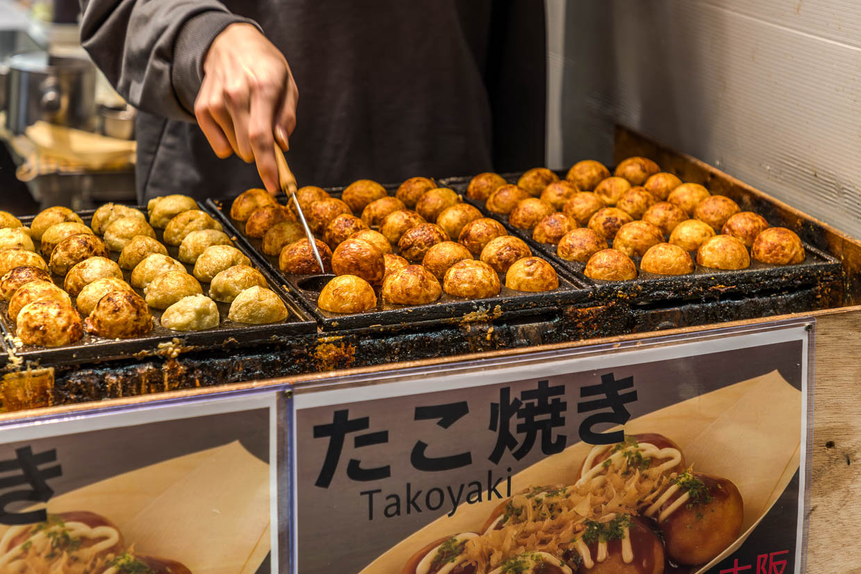 Takoyaki ist ein beliebtest Streetfood aus Osaka. Kleine Oktopusstücke werden in einem Teig aus Mehl, Eiern und Dashi-Brühe zu einer außen knusprigen Kugel gebacken / © Foto: Georg Berg