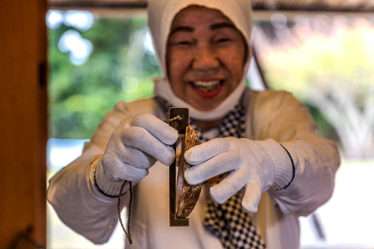 Frau mit Handschuhen präsentiert ein Objekt in Shima, Japan
