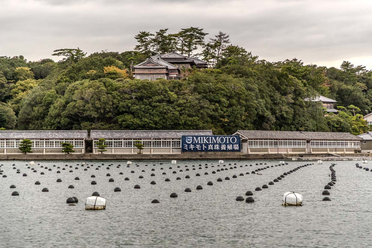 Mikimoto Perlenfarm mit Bojen im Wasser vor Gebäuden in Shima, Japan