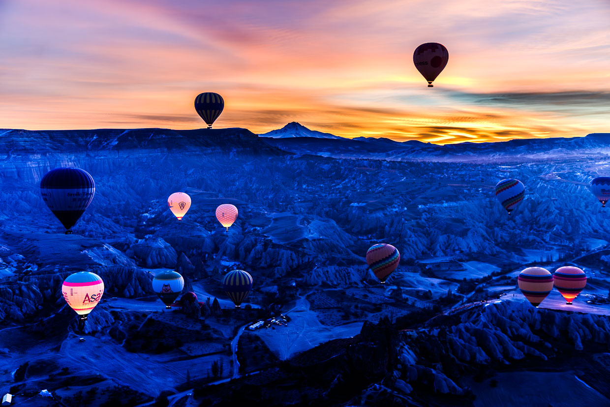 Kurz vor Sonnenaufgang hinter dem Vulkan Erciyes Dağı schweben Haißluftballons über die Tuffsteinlandschaft Kappadokiens / © Foto: Georg Berg