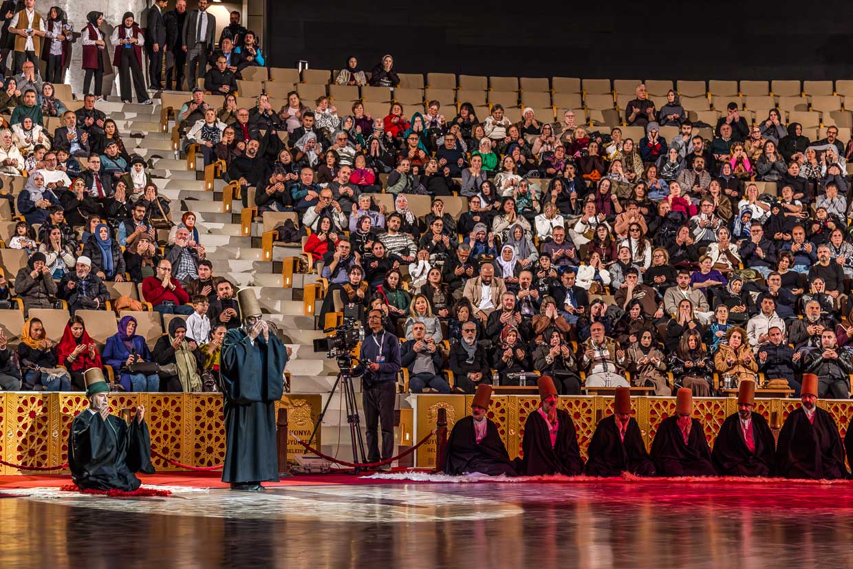 Das Ende der Şeb-i Arus-Zeremonie im 3.000 Personen fassenden Mevlana Kültür Merkezi wird mit einer Koranrezitation eingeleitet. Die Derwische sind nach ihrem Wirbeltanz wieder in ihre schwarzen Mäntel gehüllt / © Foto: Georg Berg
