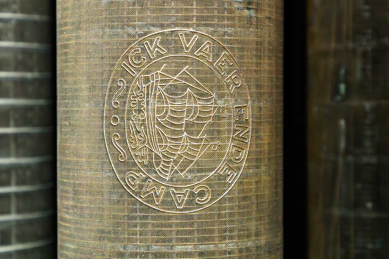 Wasserzeichen- bzw. Siebwalze eines Egoutteurs in der Sammlung des Deutschen Buch- und Schriftmuseums. Solche Walzen verbessern die Blattbildung und dienten historisch auch dazu, Wasserzeichen ins Papier zu prägen. Ein rundes Emblem mit der Aufschrift "ICK VAER ENDE CAMP" und einem Segelschiff ist zu erkennen / © Foto: Georg Berg