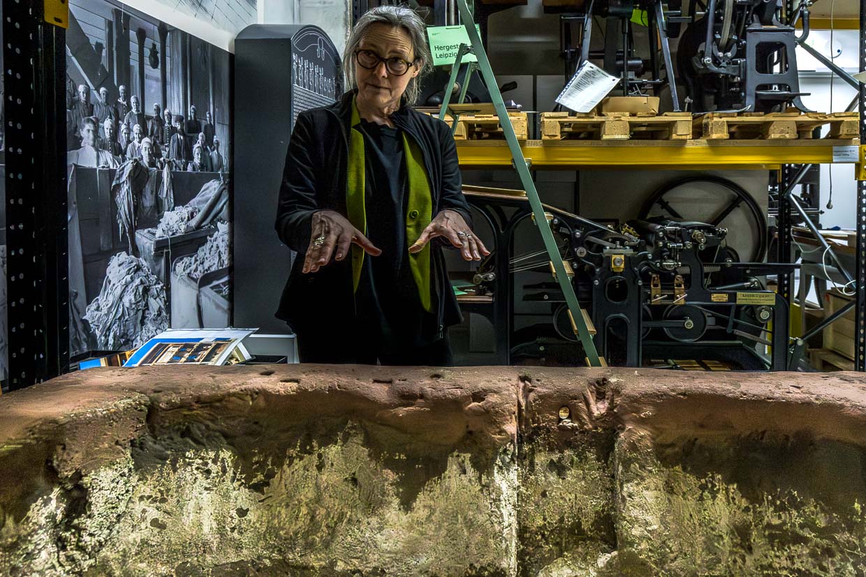 Stephanie Jacobs (Direktorien des Deutschen Buch- und Schriftmuseums) in der kulturhistorischen Sammlung mit Druckwerkzeugen. Hier ein Steintrog von 1789, in dem aus Lumpen ein Faserbrei für die Papierherstellung erzeugt wurde / © Foto: Georg Berg