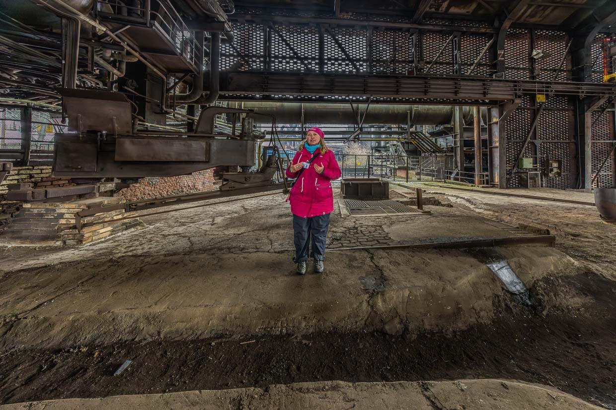 Tourguide Manuela Sass an der Abstichstelle am Hochofen Nr. 5. Er war der letzte und modernste Hochofen des Thyssen-Hüttenwerks Meiderich. Er wurde 1973 in Betrieb genommen und produzierte Spezialroheisen aus Erz bei bis zu 2.000 °C – als Vorprodukt für Thyssens Stahlwerke. Als letzter wurde er am 4. April 1985 stillgelegt, nach nur 12 Jahren aufgrund von Stahlmarktkrisen / © Foto: Georg Berg