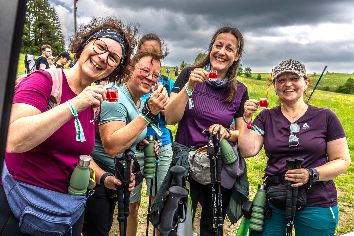 Lachende Wanderinnen feiern mit roten Getränken und Wanderstöcken Am Berg Tettau Germany beim Frankenwald-Event