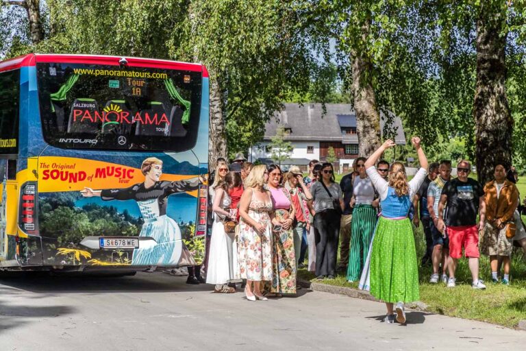 Eine Gruppe Touristen posiert am Fürstenweg in Salzburg Austria vor einem Panorama Tours Sound of Music Bus