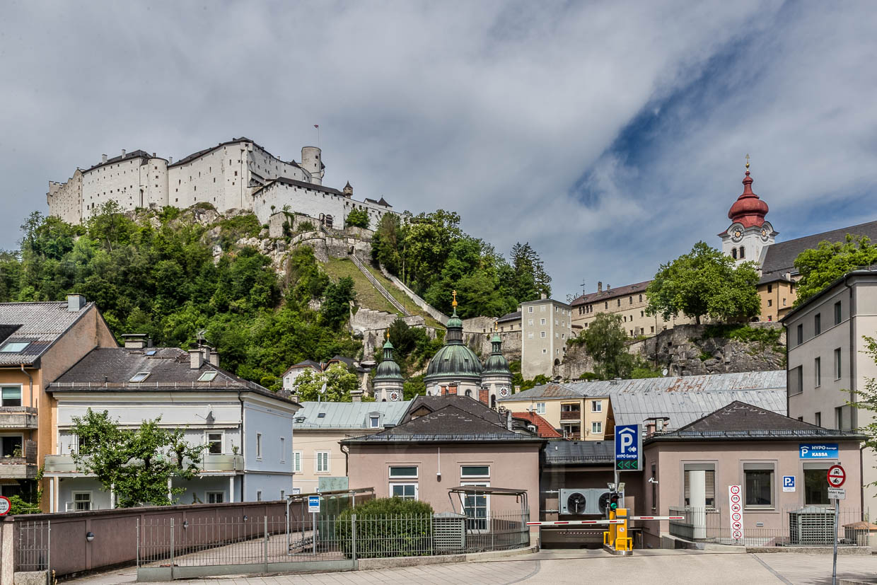 Festung Hohensalzburg und eine Kirche mit roter Kuppel überragen Gebäude und eine HYPO Garage an der Erzabt-Klotz-Straße in Salzburg Austria