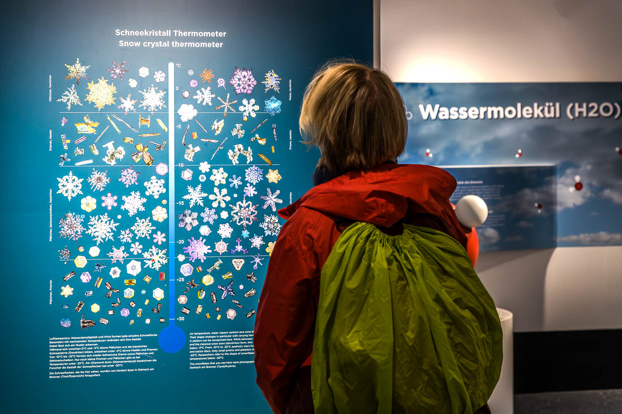 Eine Person betrachtet eine Ausstellung zum Schneekristall-Thermometer an der Gerlos Straße Krimml Austria