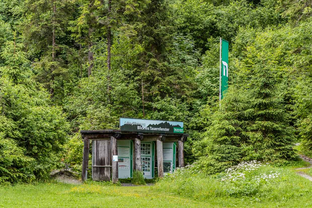 Ein Informationsstand des Geologielehrwegs und eine Nationalpark Hohe Tauern Flagge stehen am Wasserfallrundweg Untersulzbach Rosental Austria