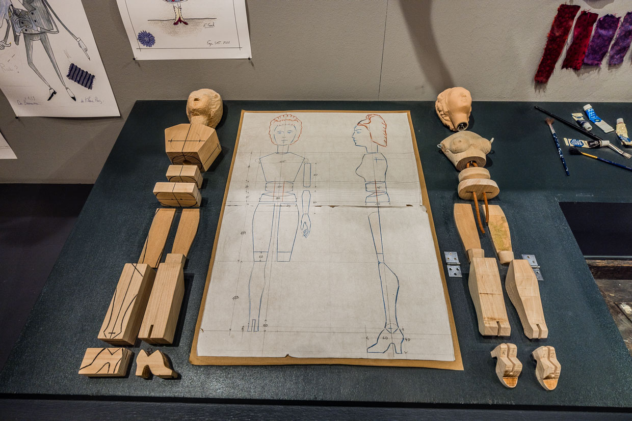 Technische Zeichnungen und Holzteile einer Gliederpuppe liegen auf einem Tisch in der Bristol-Passage Salzburg Austria