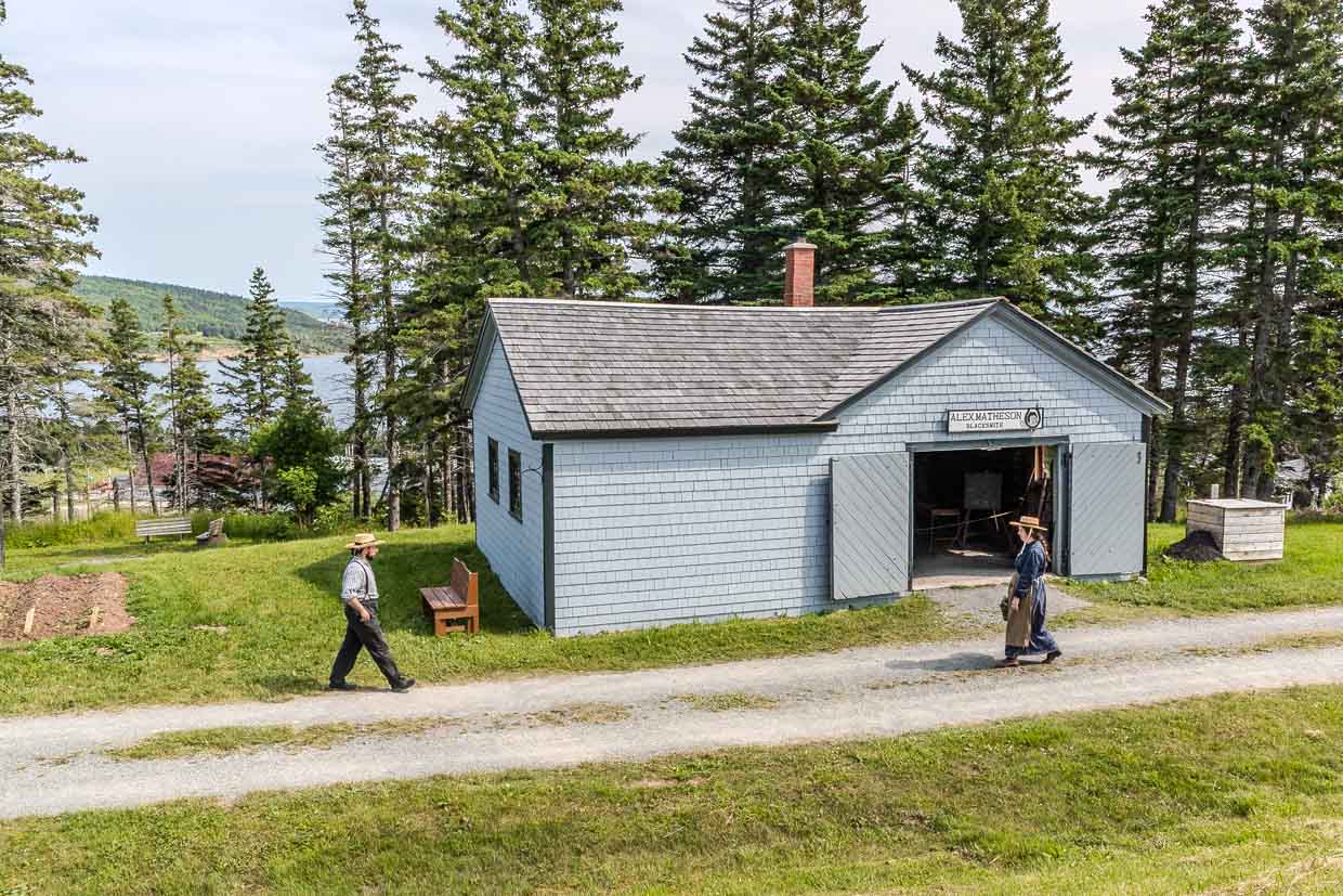 Zwei Personen gehen auf einem Schotterweg vor der Alex Matheson Schmiede in Iona, Kanada