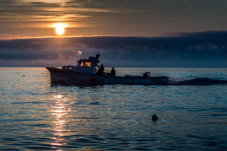 Fischerboot fährt bei Sonnenaufgang auf dem Meer vor Indian Brook, Canada