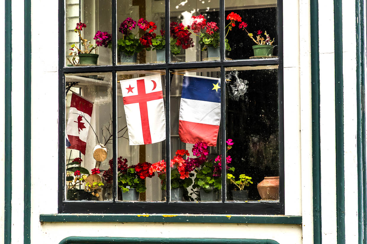Blumen und Flaggen schmücken ein Fenster an der Old Post Road, Grand Pre, Canada