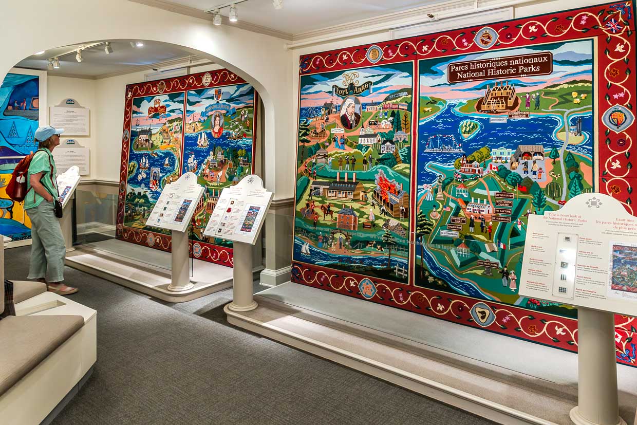 Besucherin betrachtet historische Wandteppiche im Museum am Counterscarp path, Annapolis Royal, Canada