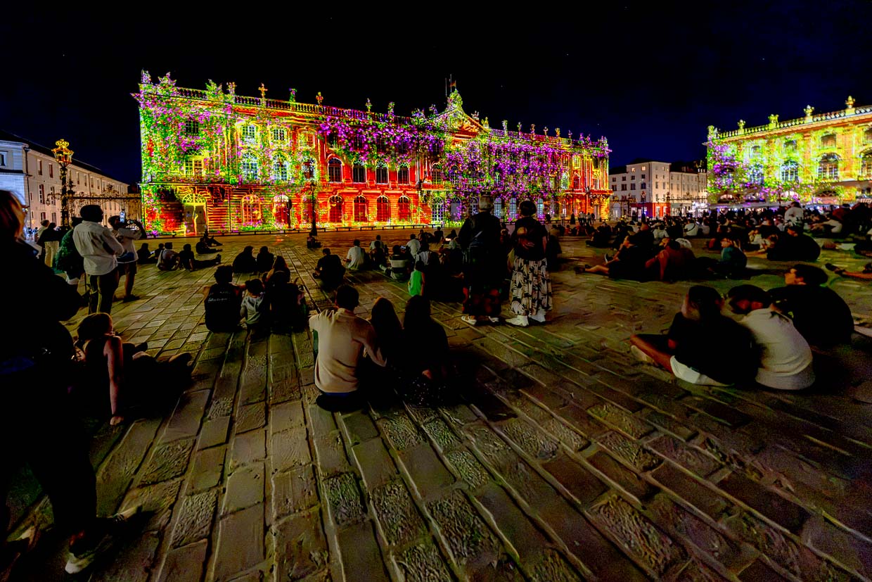 Menschen beobachten eine Lichtshow auf dem Place Stanislas in Nancy, Frankreich